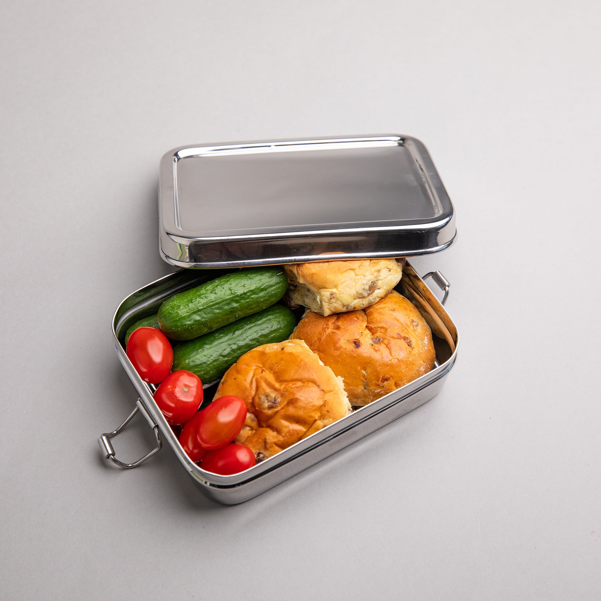 RVS broodtrommel gevuld met komkommer tomaten en brood. 