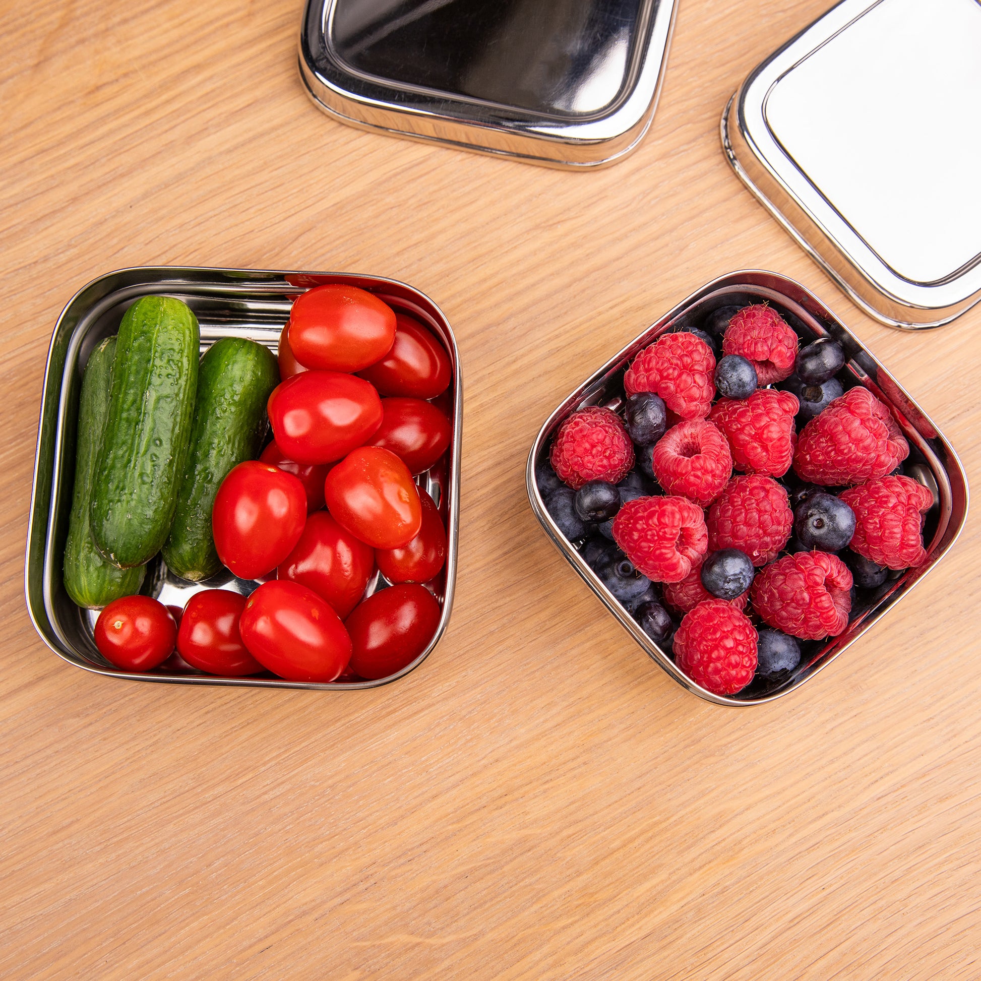 RVS fruitbakjes op een schoolafel met groenten en fruit