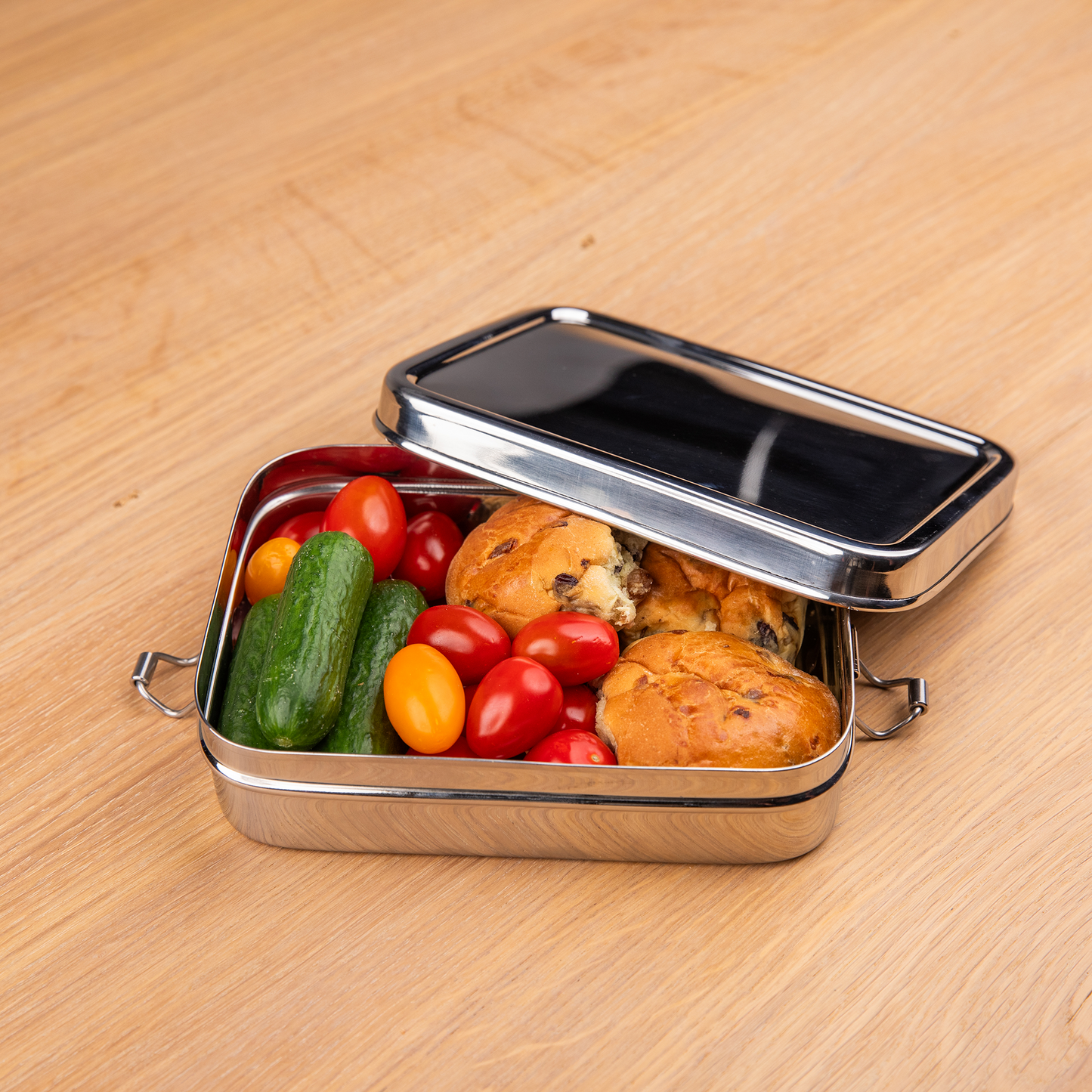 RVS lunchbox gevuld met brood en groenten op een schooltafel