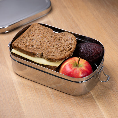 RVS lunchbox gevuld met brood en appel op een houten ondergrond met een deksel erlangs