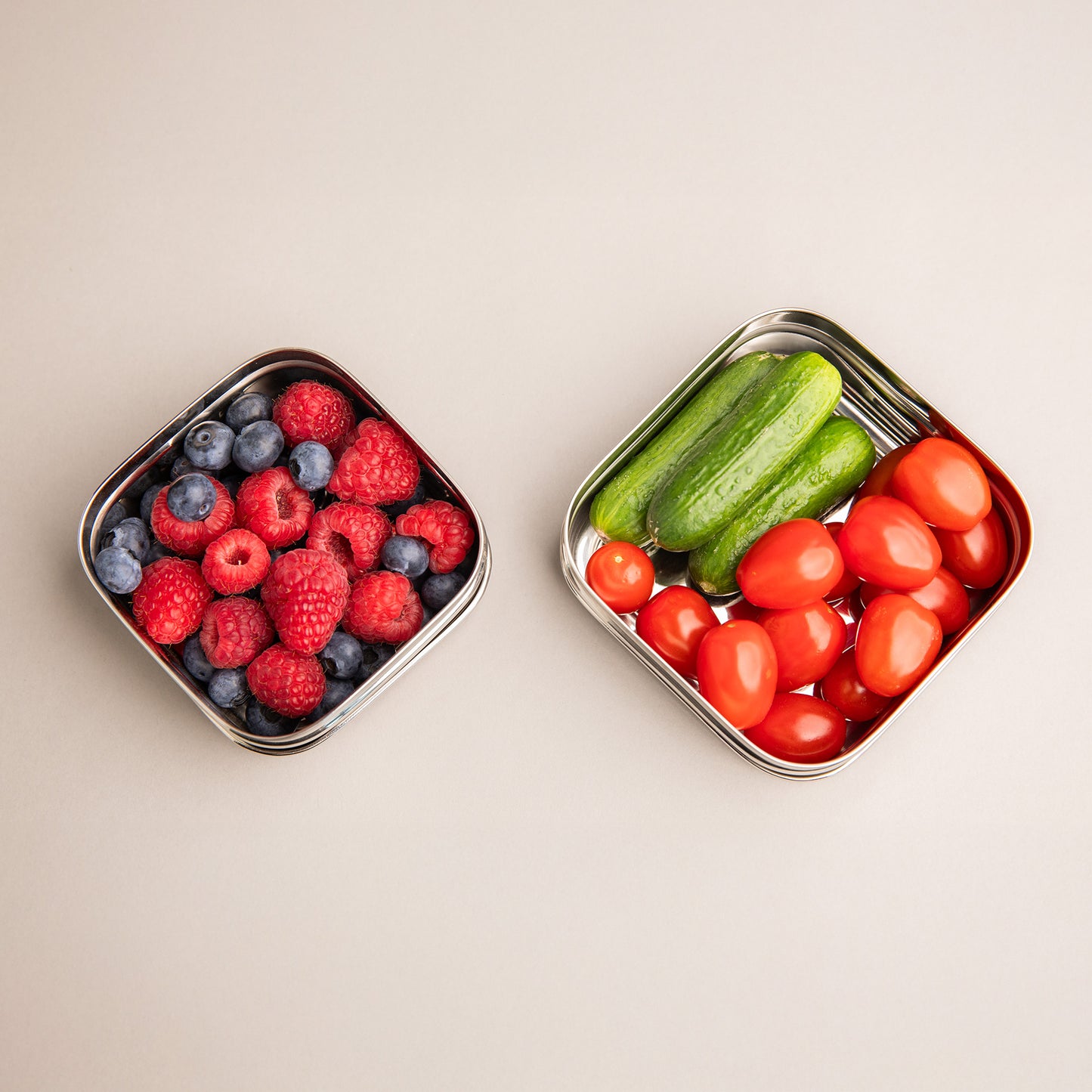 twee rvs snackboxjes gevuld met fruit en groenten