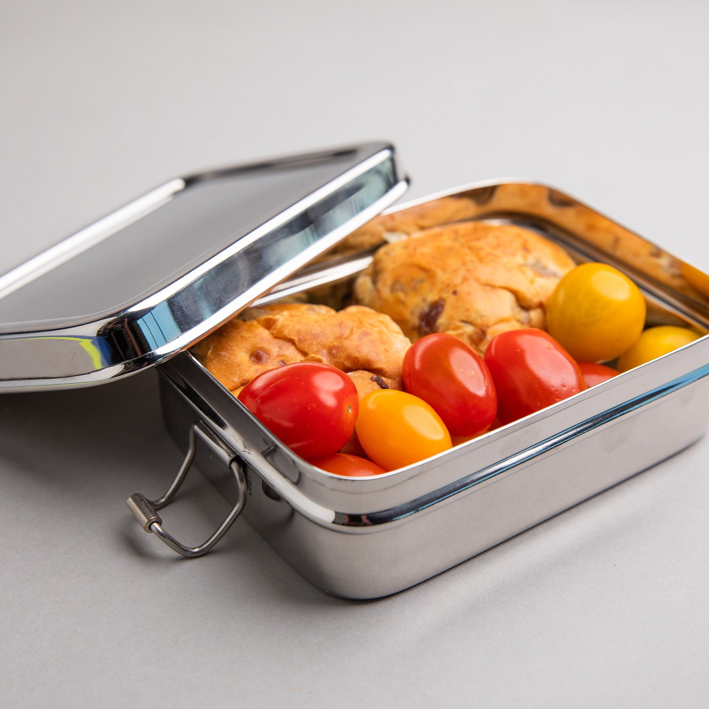 RVS lunchbox gevuld met tomaten en krentebollen