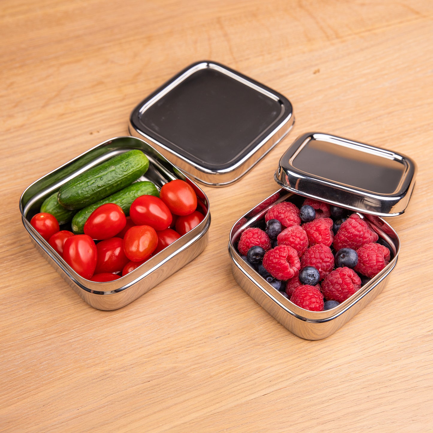 RVS snackboxen op een schooltafel gevuld met groenten en fruit